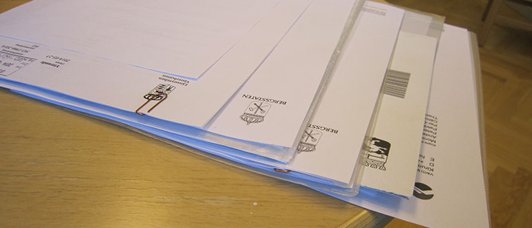 Papper ligger i buntar på ett skrivbord. Foto.