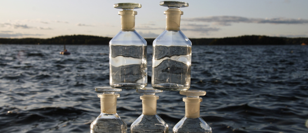 En sjö med vattenflaskor staplade på varandra i förgrunden. Foto.
