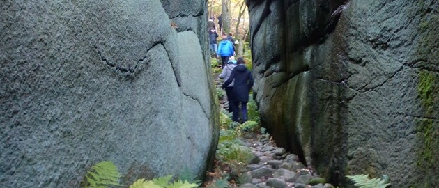 Två personer passerar genom en djup bergsklyfta. Foto.