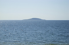 Vatten och i horisonten syns en ö. Foto.