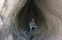 En man står i öppningen till en så kallad lökgrotta. Härnökusten. Foto.