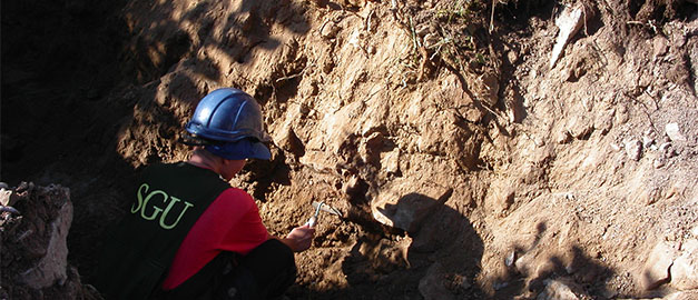 Geolog putsar grop i morän. Foto.