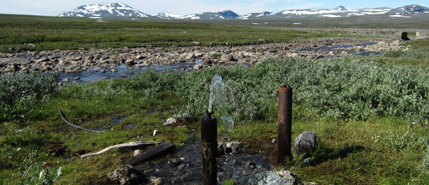 Vatten som sprutar ur rör. Fjäll i bakgrunden.