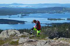 En man står på en klippa. Havet syns nedanför. Foto.