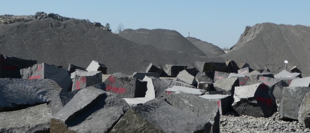 Fotografi på block av natursten med högar av ballast i bakgrunden. 