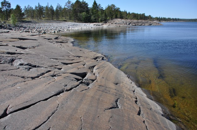 Släta klippor, vatten och skog. Foto.