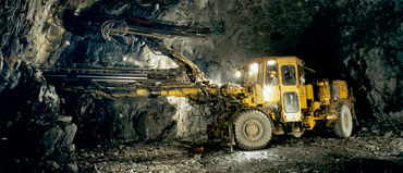  A type of drill used in mines to drill into the rock. The drill is attached to a tractor-like vehicle. Photo.